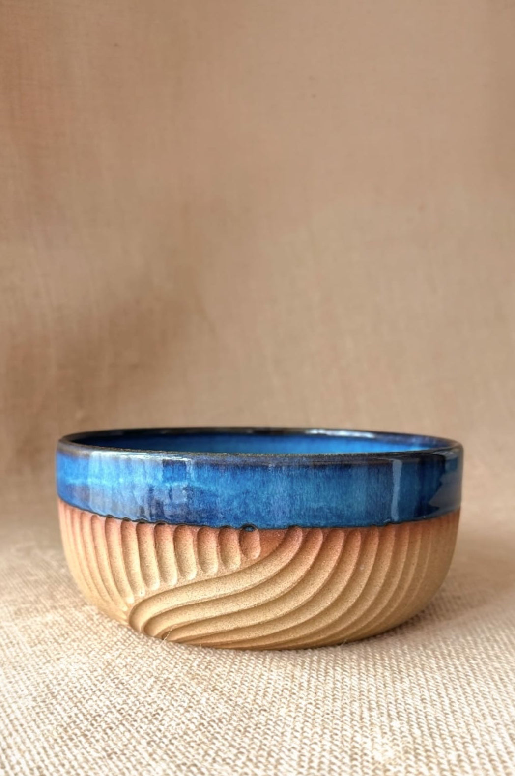 Ceramic bowl with blue interior and beige exterior on a beige background