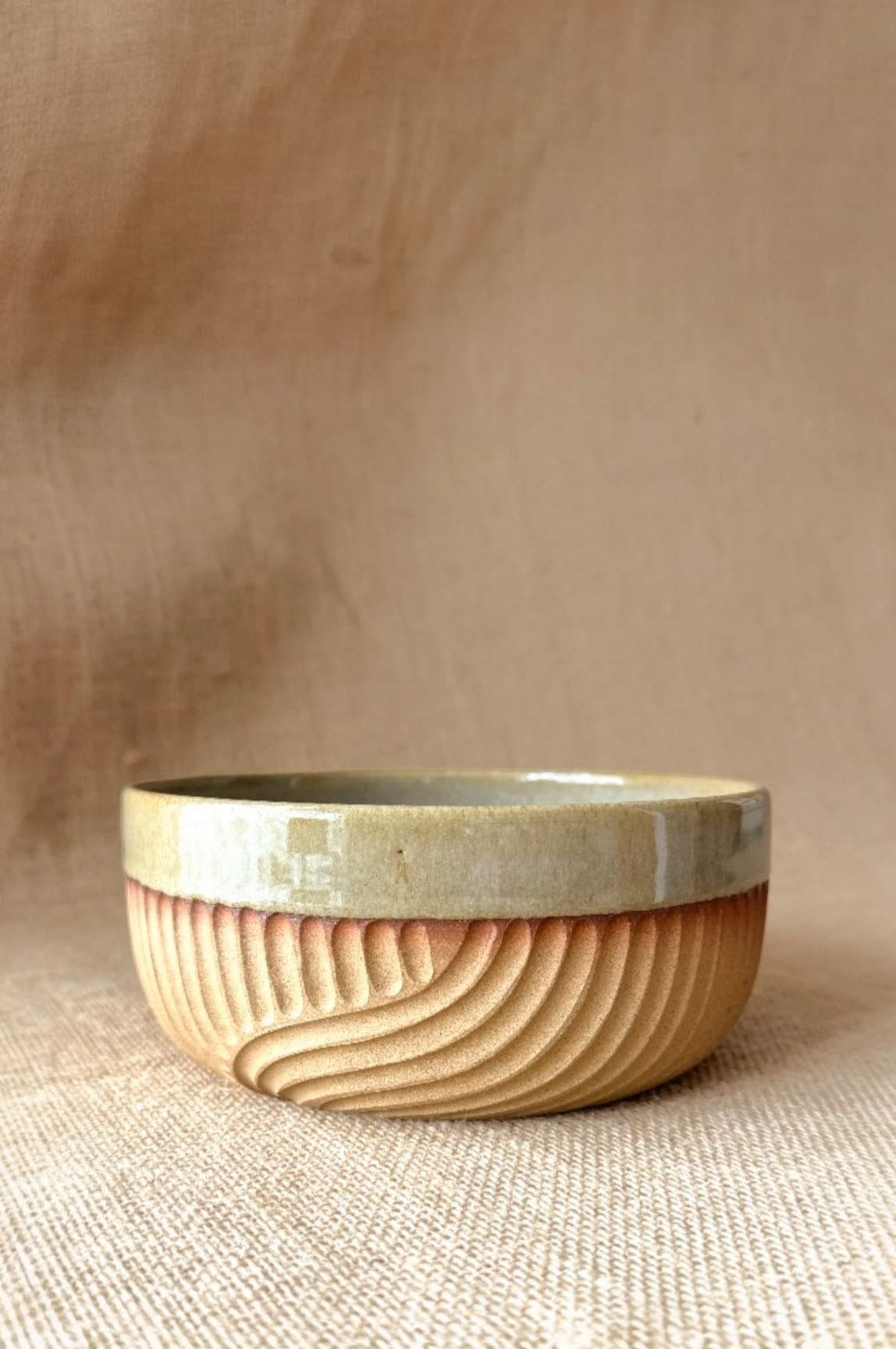 Ceramic bowl with natural wood finish on a beige background