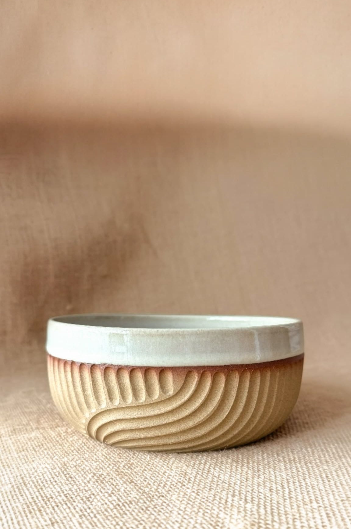Ceramic bowl with wavy design on a beige background