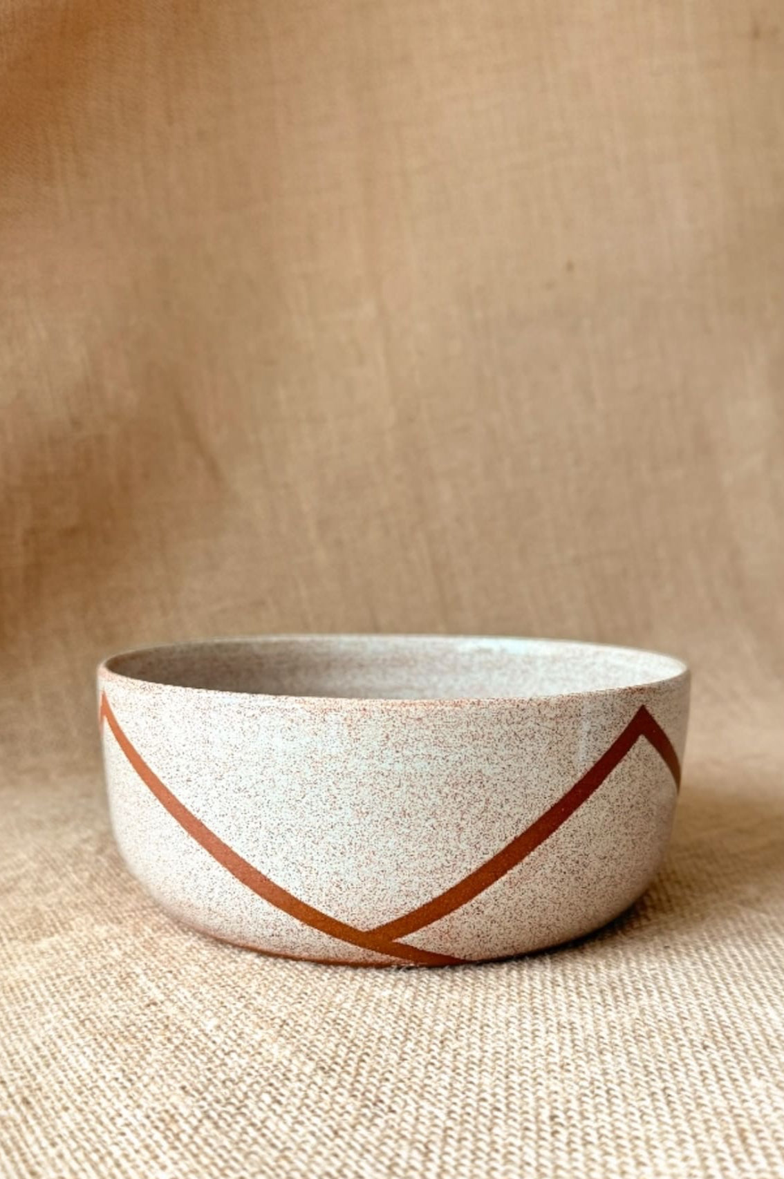 Ceramic bowl with a geometric design on a textured beige background