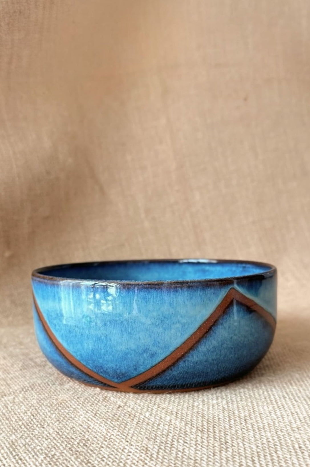 Blue ceramic bowl with brown accents on a beige background