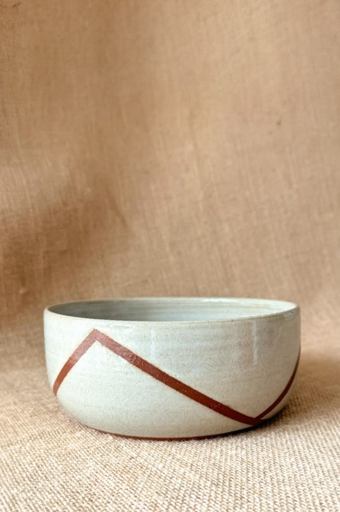 Ceramic bowl with red geometric design on a beige background
