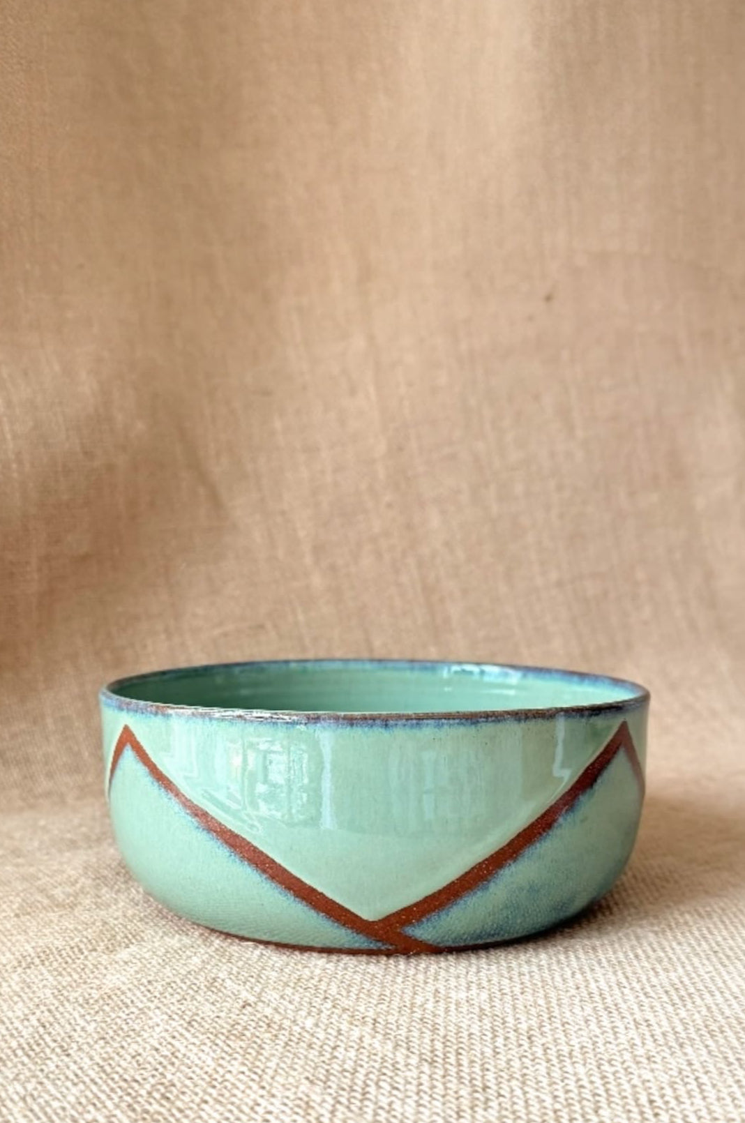 Turquoise ceramic bowl with brown accents on a beige background