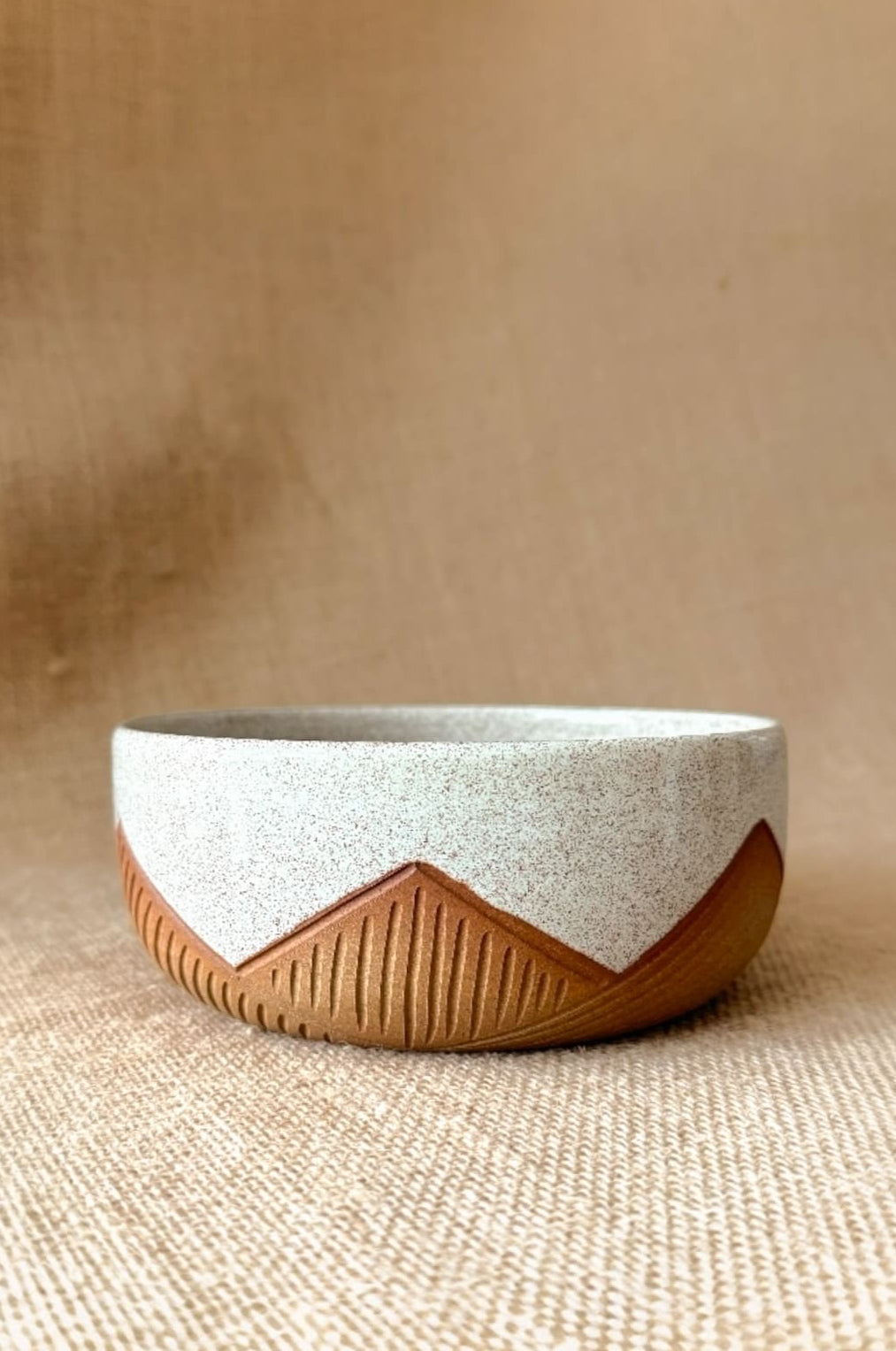 Ceramic bowl with wooden base on a textured beige background