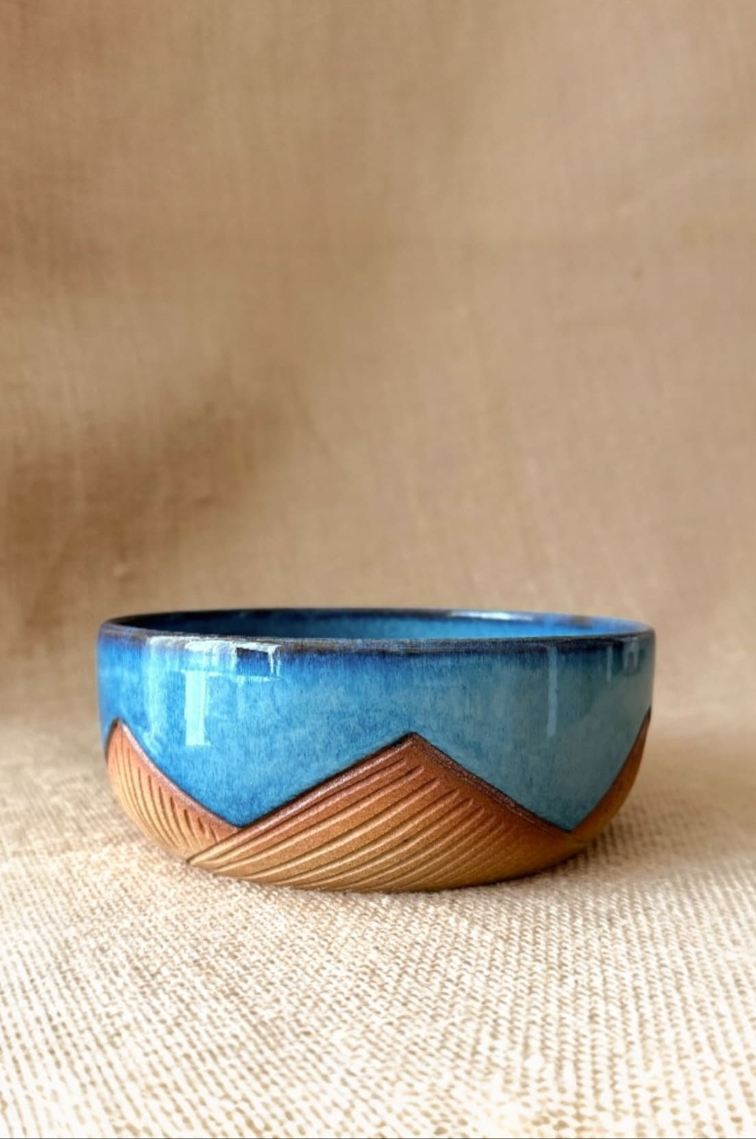 Ceramic bowl with blue top and brown bottom on a beige background
