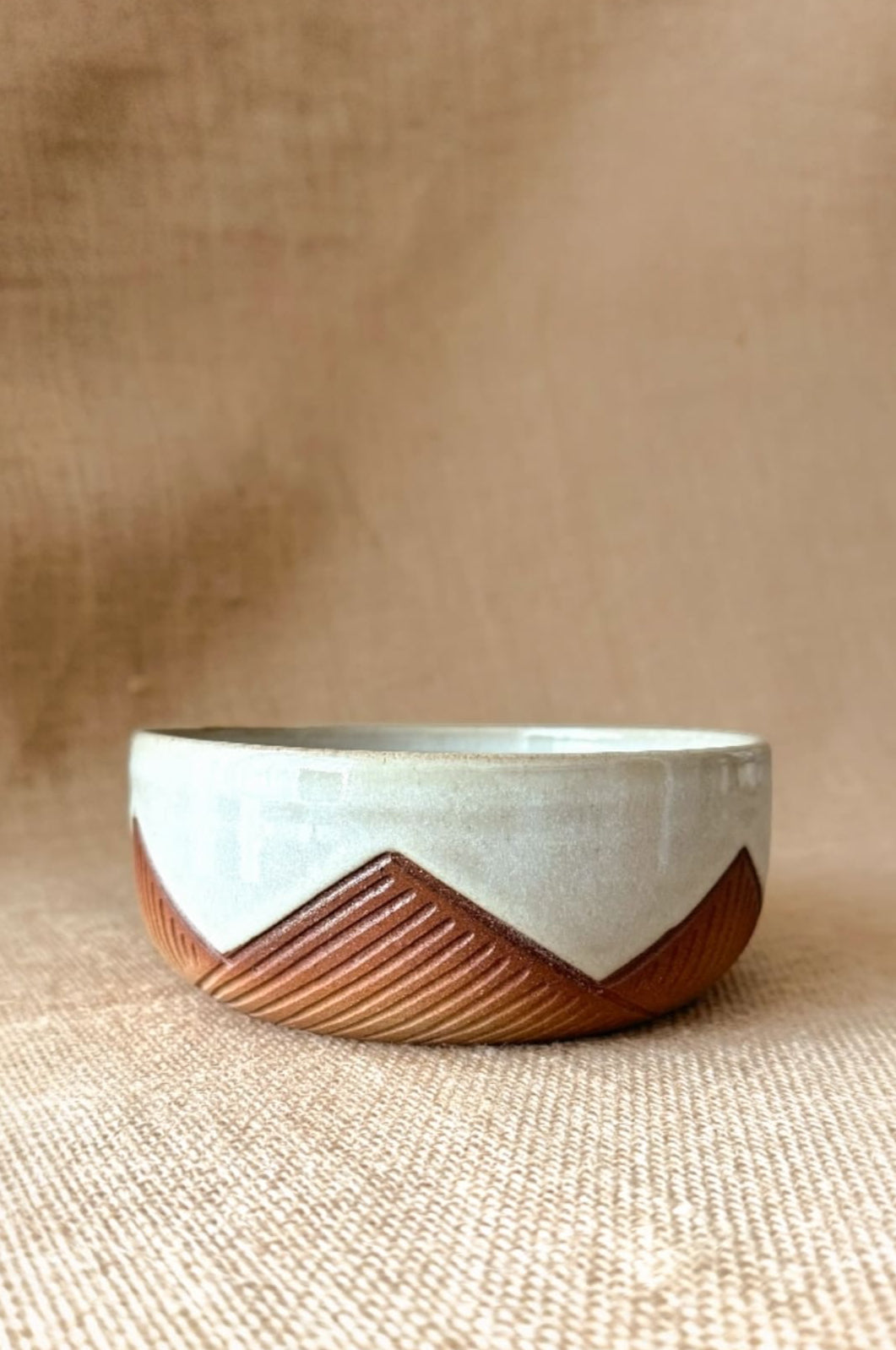 Ceramic bowl with wooden base on a beige fabric background