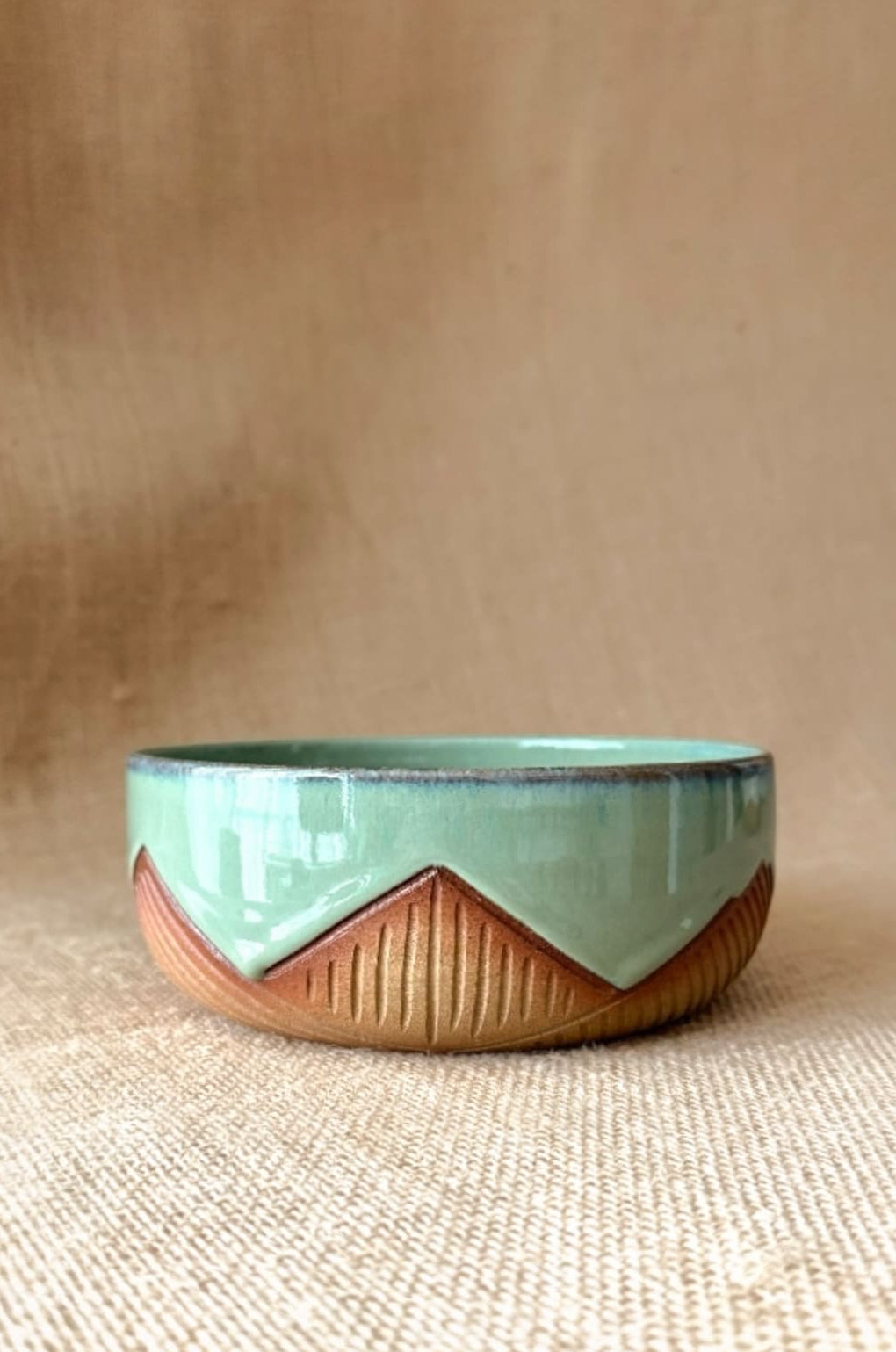 Ceramic bowl with green top and brown bottom on a beige background